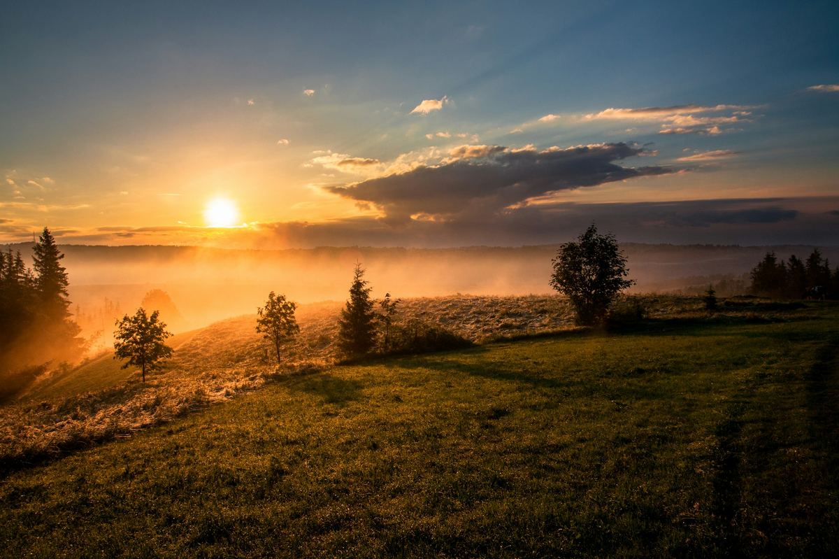Sunrise breaking over open fields — light overcoming darkness